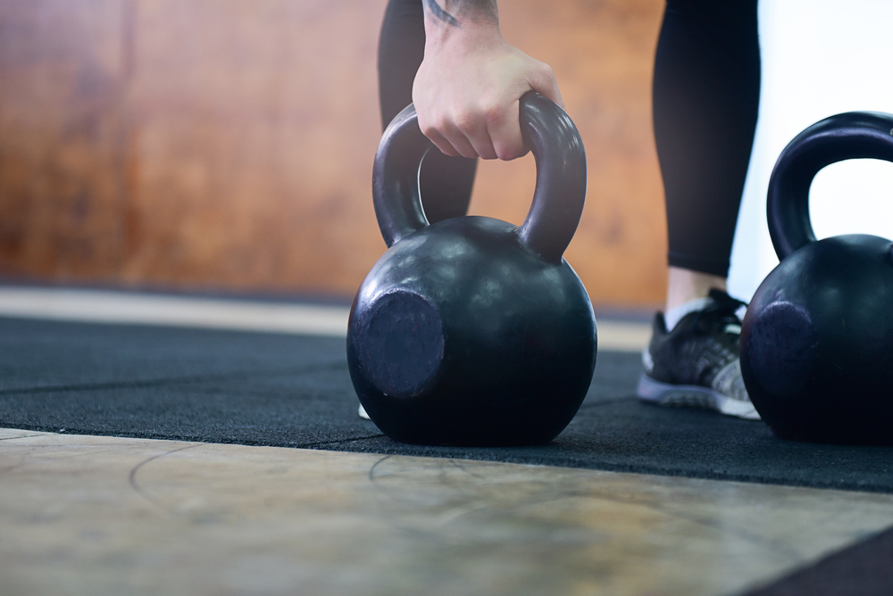 en kvinna som håller i en kettlebell för att göra styrkelyft eller hemmaträning med den